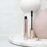 Rose gold mascara with interchangable brush Audrey sitting in a beautiful bathroom with pearl earrings 